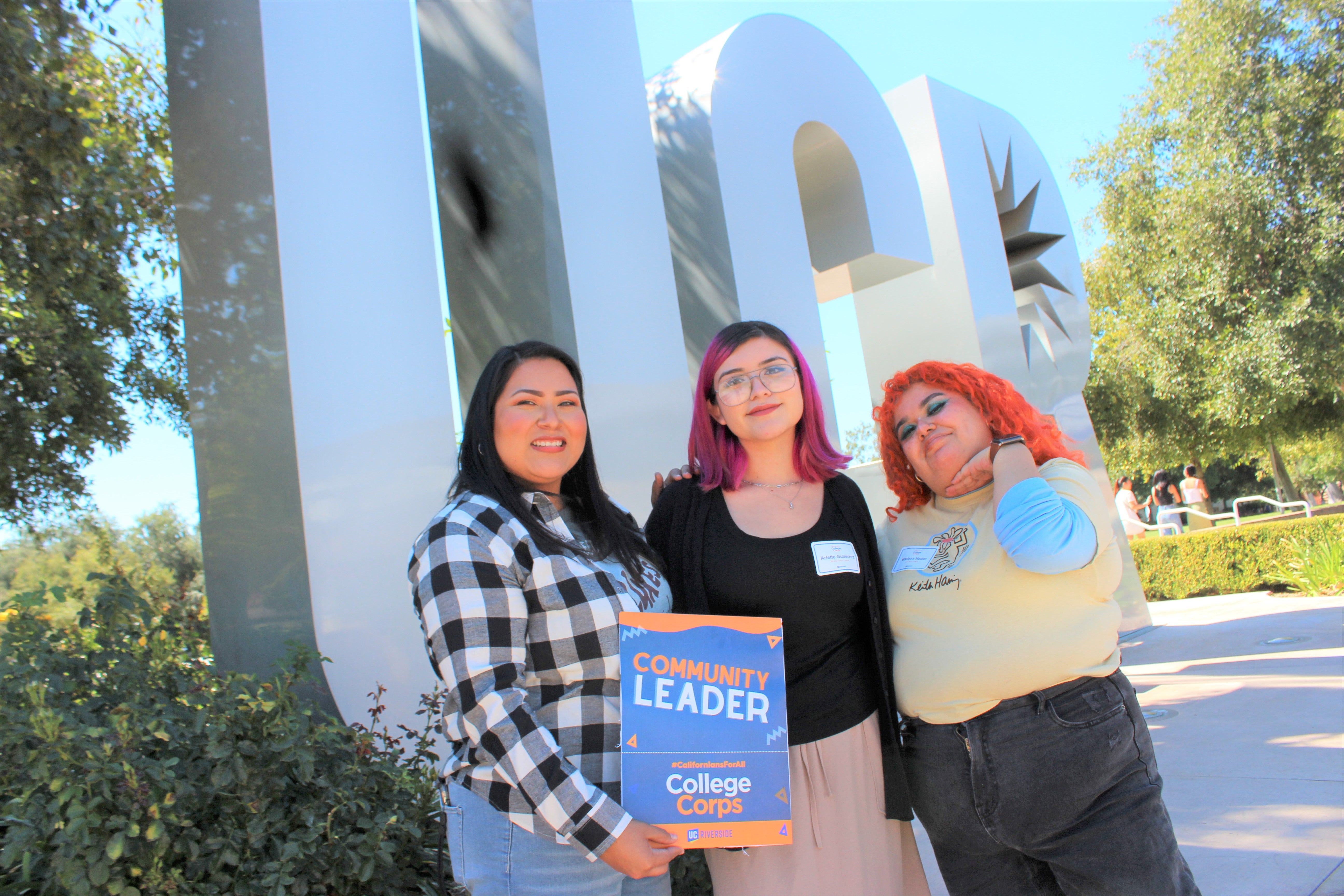 Three students in front of UCR sign